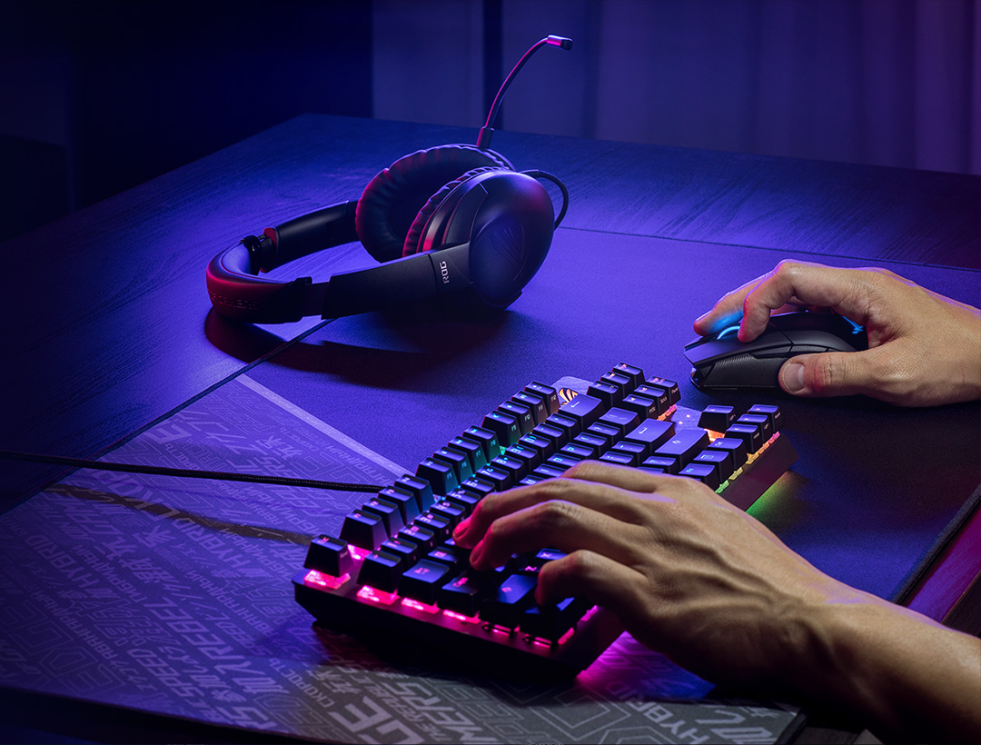 A gamer playing with the ROG keyboard and mouse, an ROG Strix Go seen on the left of the image