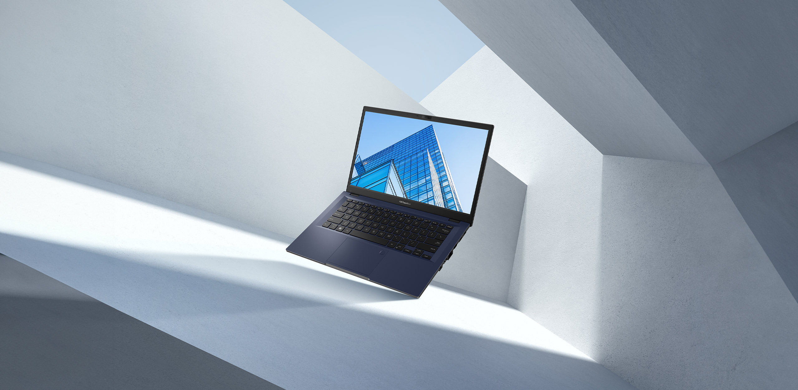 ASUS ExpertBook B1, sur fond de ciel bleu et d'architecture minimaliste.