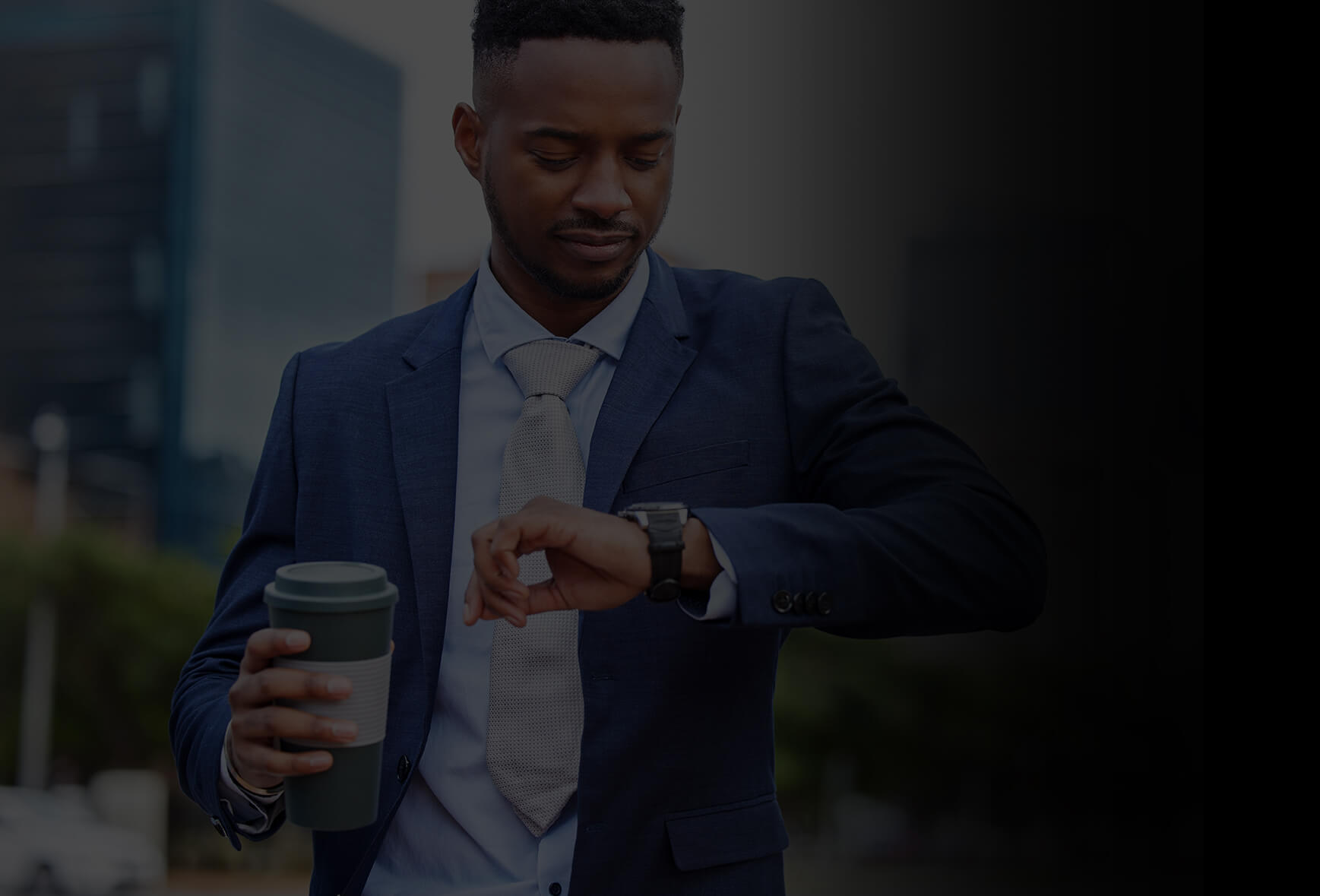 A business man outside office building is looking at his smart watch to check weather and holding a cup of coffee on the other hand