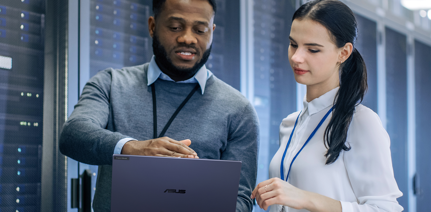 Deux membres du personnel informatique consultent un ASUS ExpertBook B5 et discutent ensemble dans un centre de données.