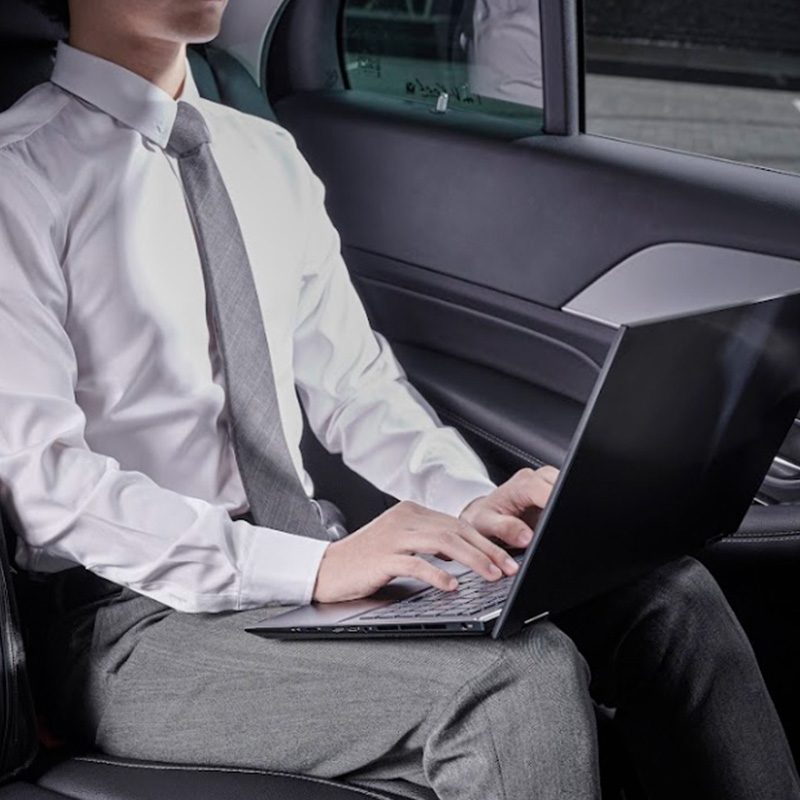 a businessman in professional attire sitting on the car, working on the go on an ASUS laptop with his ASUS Collection Vantage laptop briefcase next to him