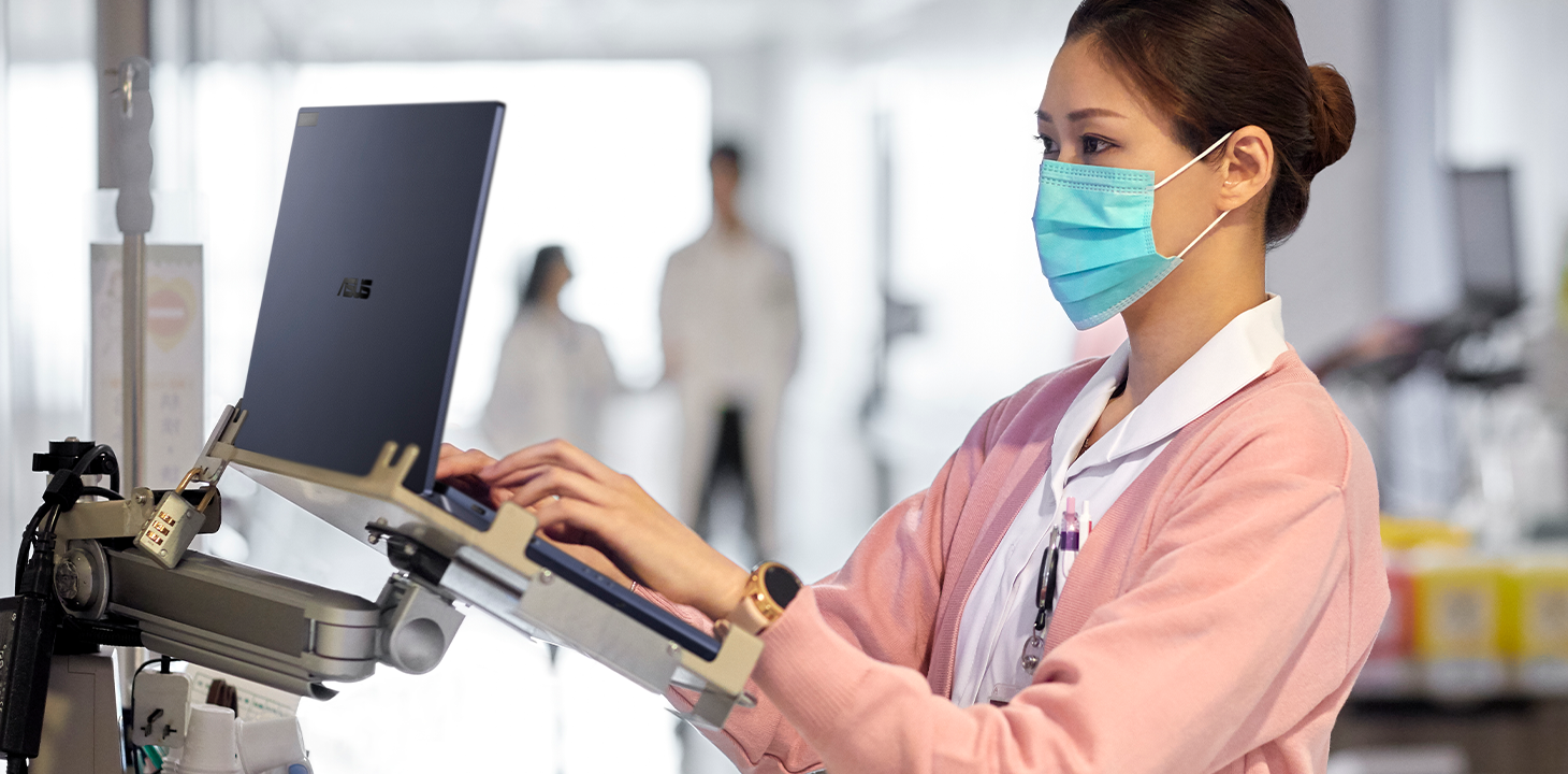 Eine Krankenschwester tippt auf dem ASUS ExpertBook auf einer mobilen Arbeitsstation.
