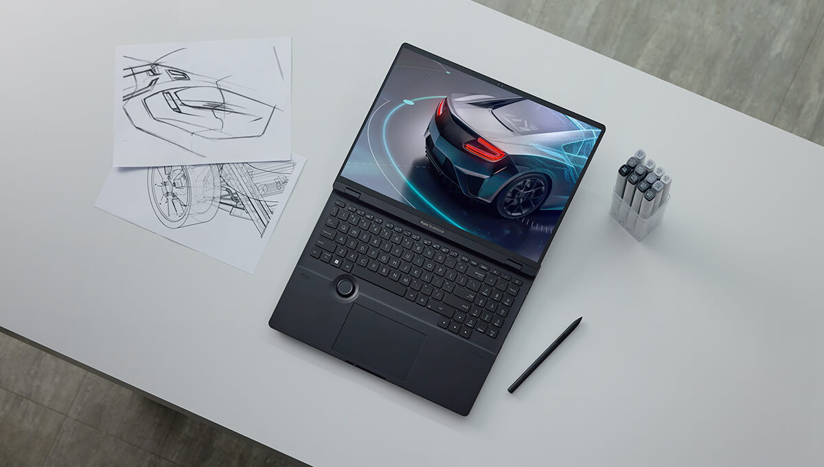 ProArt Studiobook lies open on a white table and the screen shows a modern looking car with high tech lighting decorations. There’re few car sketches, one stylus and a marker set next to the laptop