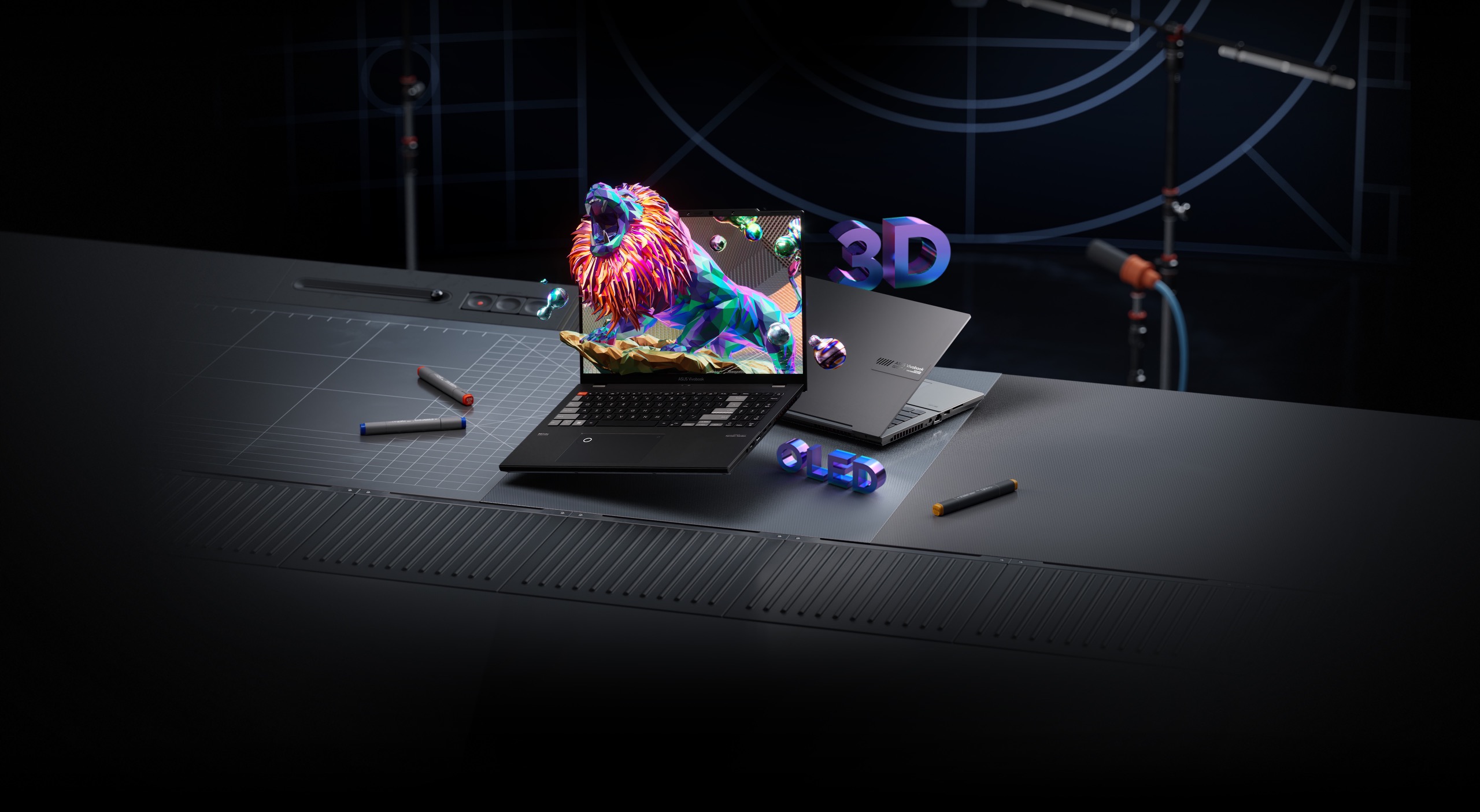 На столе в студии показаны два ноутбука Vivobook Pro 16X 3D OLED: черный и серебристый. На экране черного виден ревущий лев