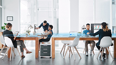 Ett modernt kontor med fem personer som tittar på skärmar. ASUS affärsprogram visas på skärmen.