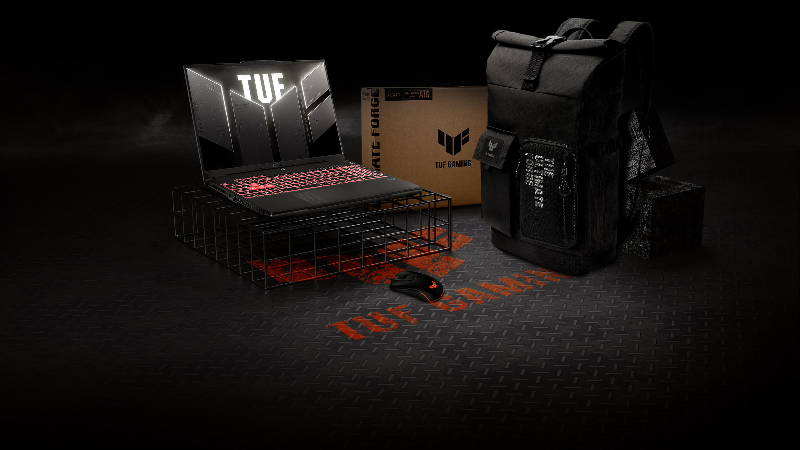 Ноутбук TUF Gaming A16 стоит на проволочной подставке. Рядом с ним находятся мышь и рюкзак серии TUF Gaming.