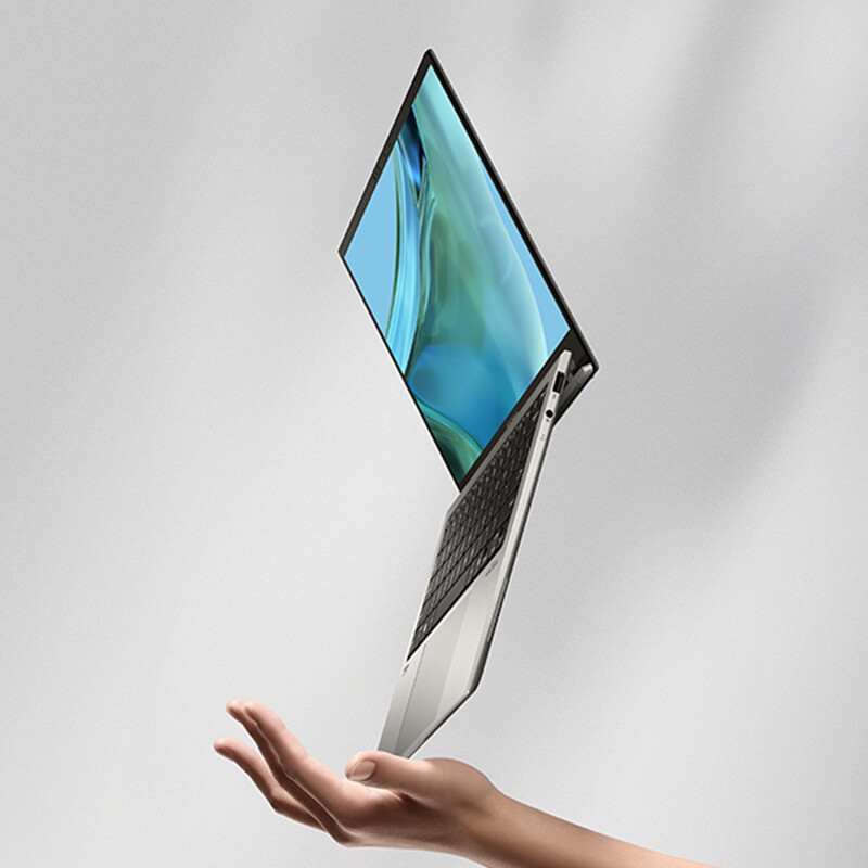 An open Zenbook S 13 OLED laptop, balancing on a corner on an open palm of a woman’s hand