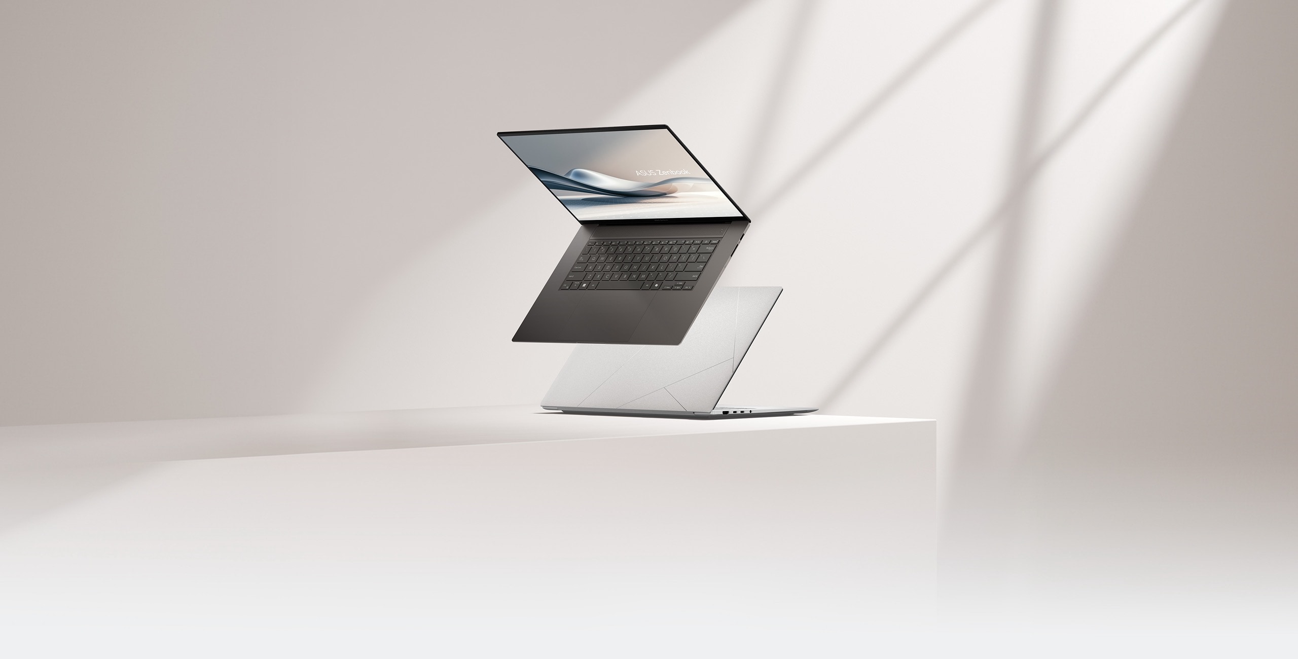 Dos Zenbook S16, uno de ellos abierto a 100 grados y visto desde el frente izquierdo, mientras que el otro está cerrado y colocado en el suelo.