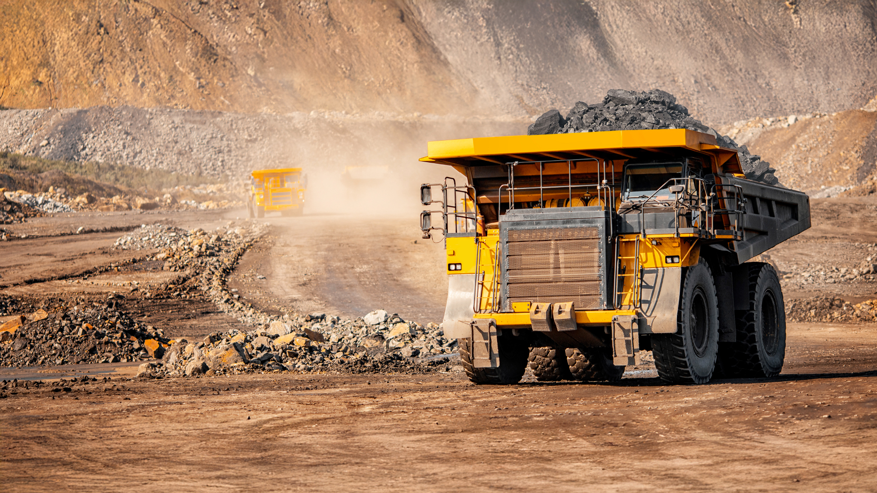 Mining Site with Heavy Trucks Mining operation scene with large trucks working in a rugged, dusty terrain