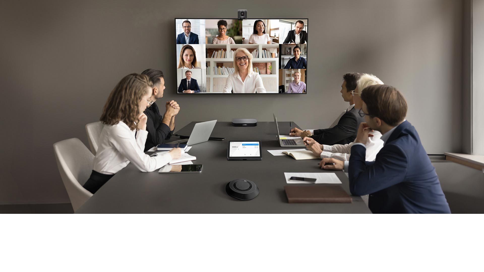 A group of people having a video conference in a meeting room, with Google Meet Hardware kit on the table