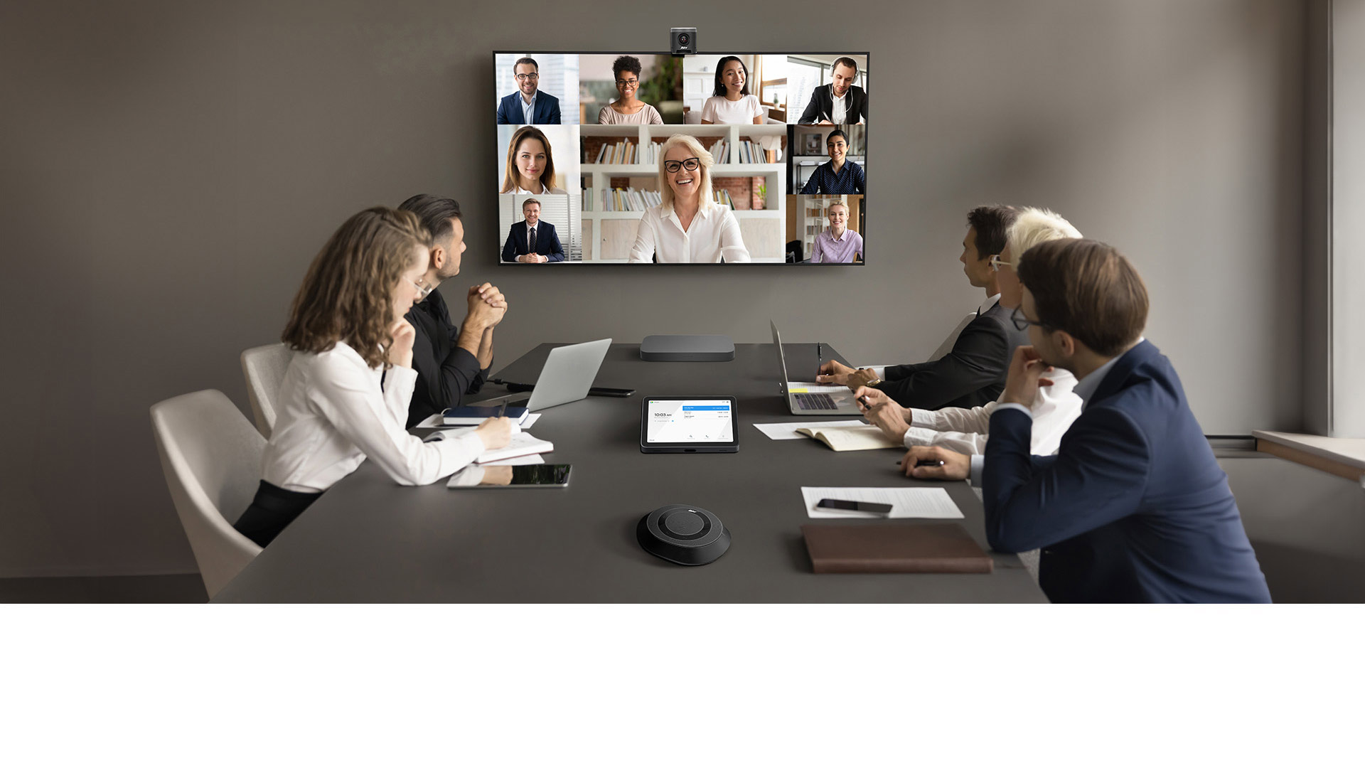 A group of people having a video conference in a meeting room, with ASUS Room Kit for Google Meet on the table