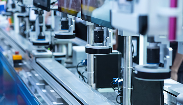A machine operates on a conveyor belt, processing items alongside another machine in a factory setting.