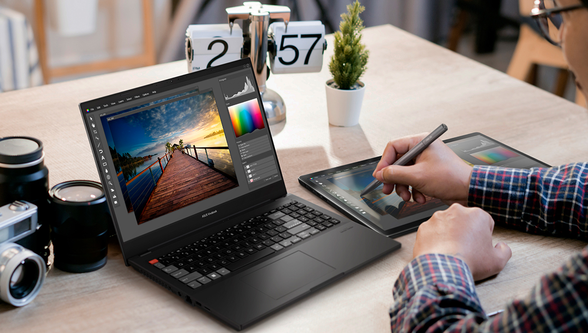 a content creator using ASUS Vivobook Pro creator laptop and a pen tablet to edit photos at the desk with a camera next to the laptop