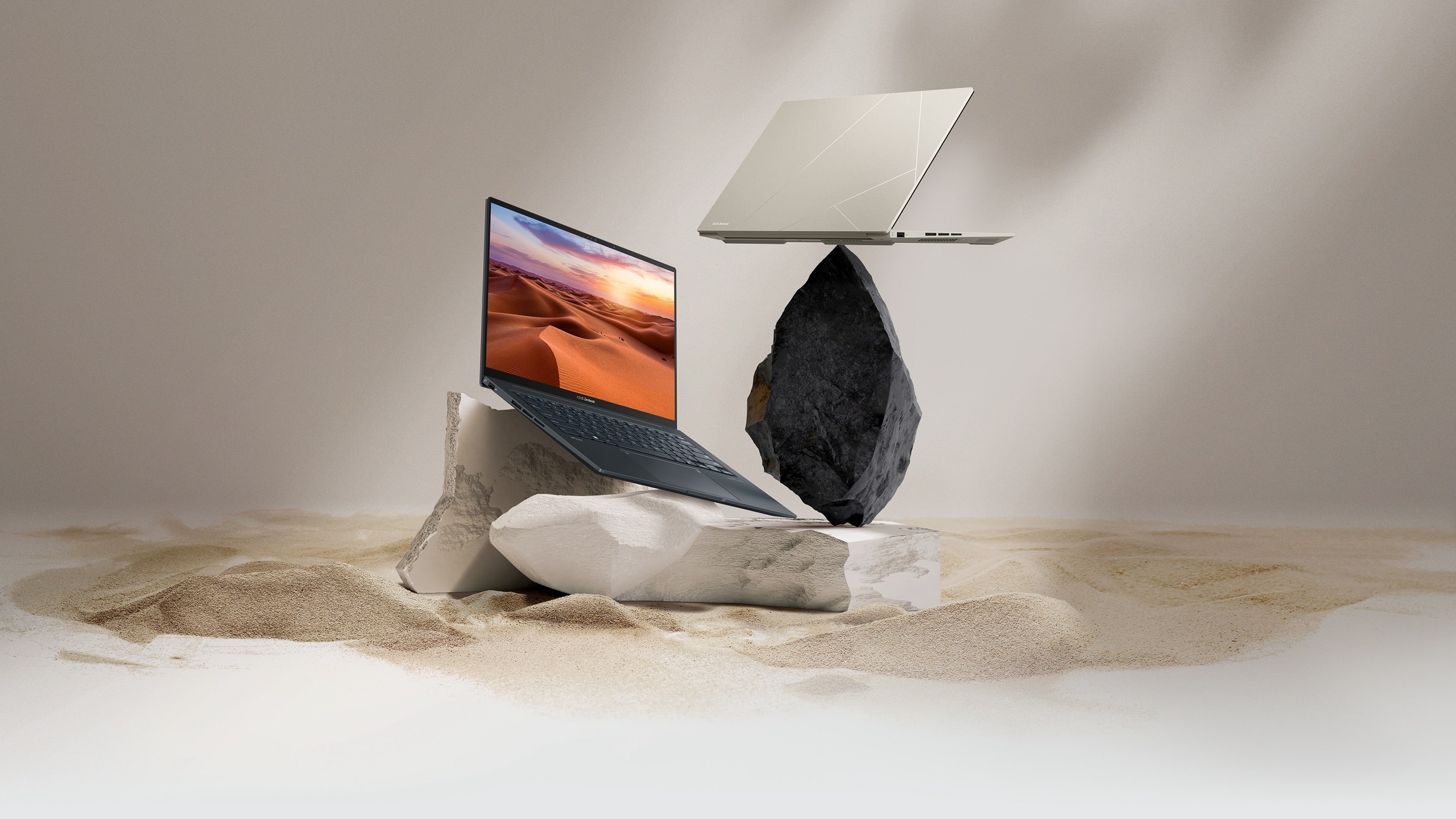 En sort og en beige Zenbook 14X OLED. Den sorte er åbnet vidt på en sandstensklippe, og den beigefarvede er vist bagfra på en sort klippe.