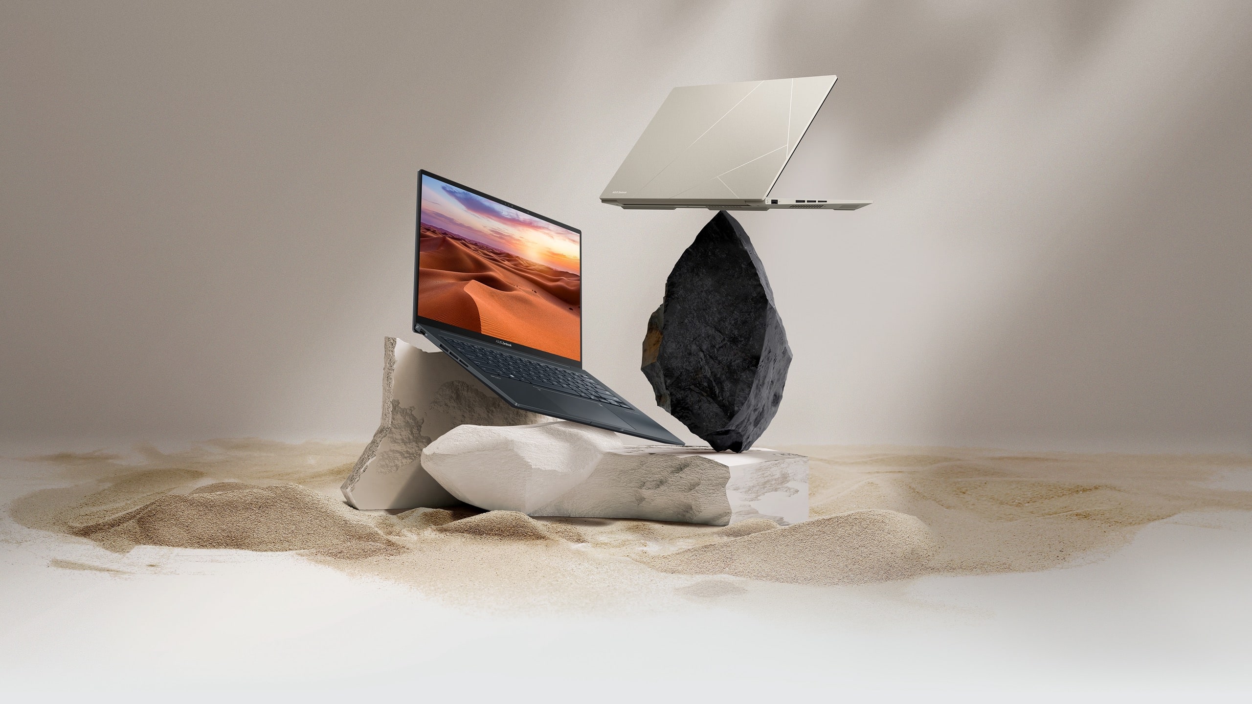 A black and a beige Zenbook 14X OLED. The black one is wide open on a sandstone rock, and the beige one is seen from behind on a black rock.