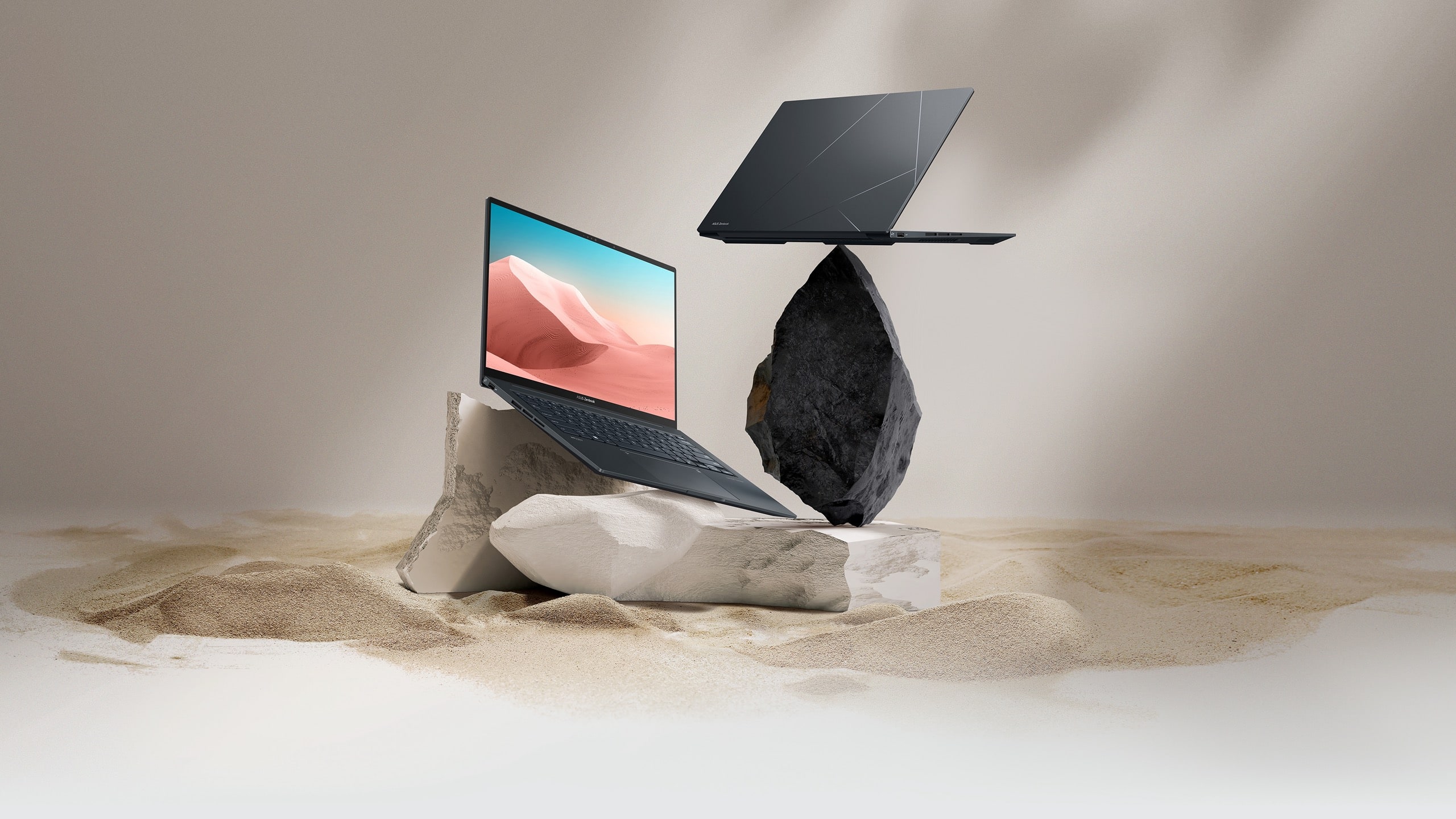Two black Zenbook 14X OLED. The One is wide open on a sandstone rock, and the other one is seen from behind on a black rock.