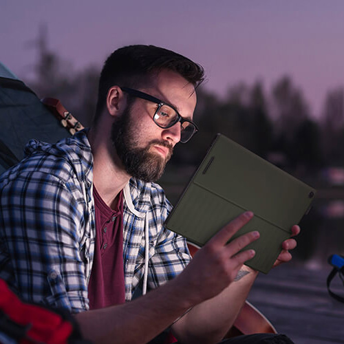 a content creator sitting in front of a tent, holding a ProArt PZ13 device in hands