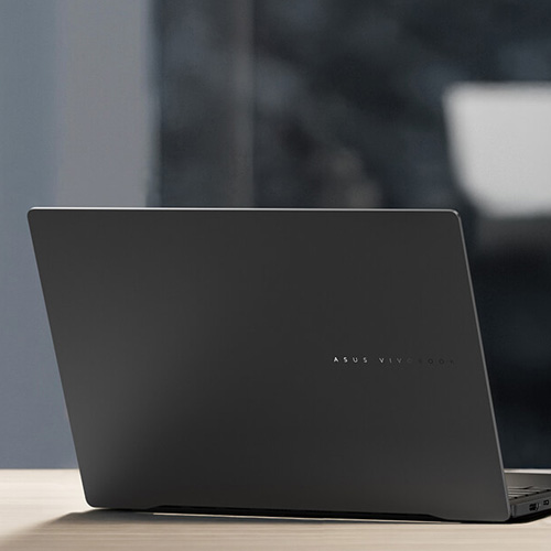 An ASUS Vivobook S 14 laptop on a desk, with a cup of coffee next to it