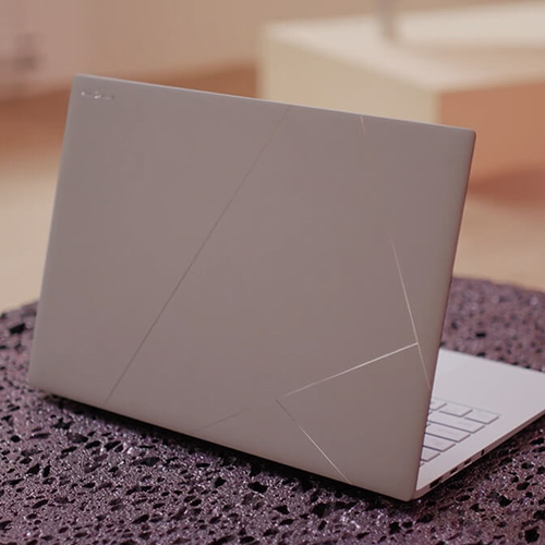 A Zumaia Grey ASUS Zenbook is placed on a surface that has a lava-like texture.