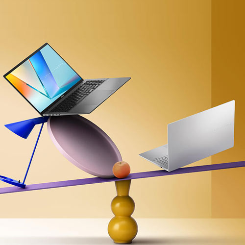 Two ASUS Vivobooks balanced on geometric shapes in front of a yellow background.