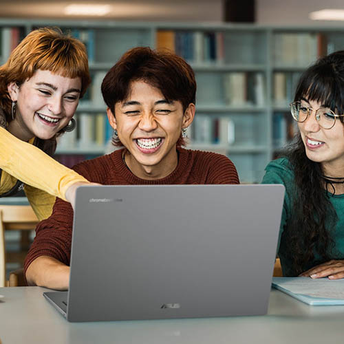 Dört öğrenci, kütüphanedeki bir masanın üzerinde duran açık bir ASUS Chromebook dizüstü bilgisayarın etrafında toplanıyor