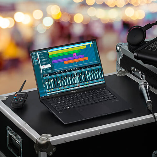 Zenbook Pro 14 OLED на рабочем месте звукооператора во время уличного мероприятия. Рядом с ноутбуком видны наушники и звуковая консоль.