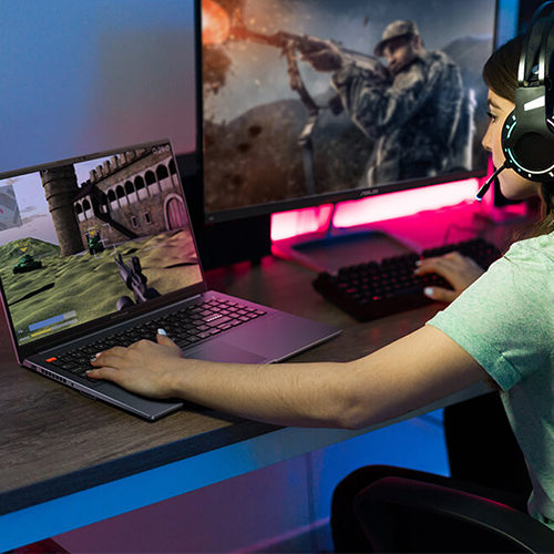 A girl uses an ASUS Vivobook Pro 15 OLED laptop to play an FPS game while sitting at her desk