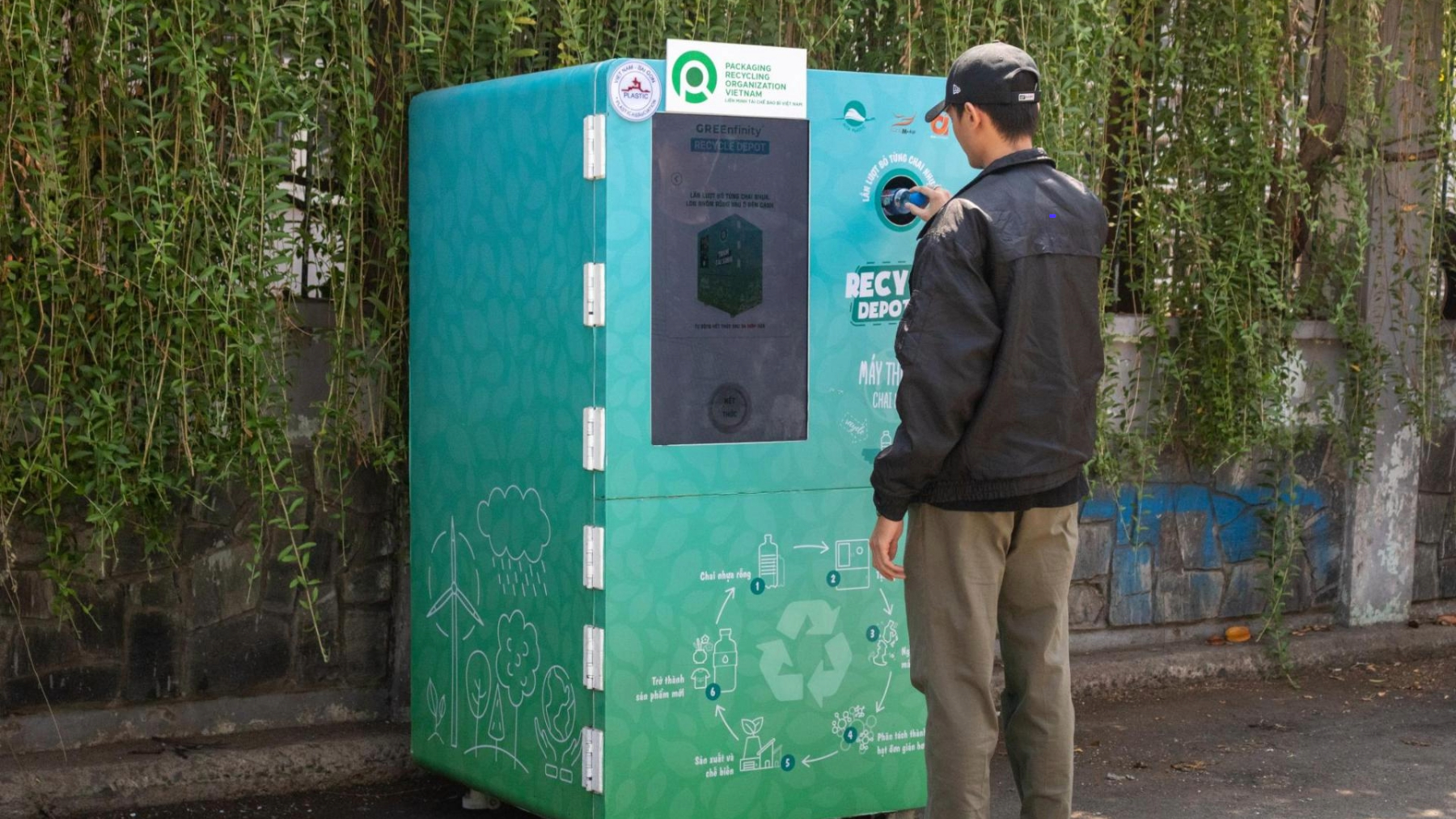 A man with hat on standing in front of Alta Media’s Recycling vending machine