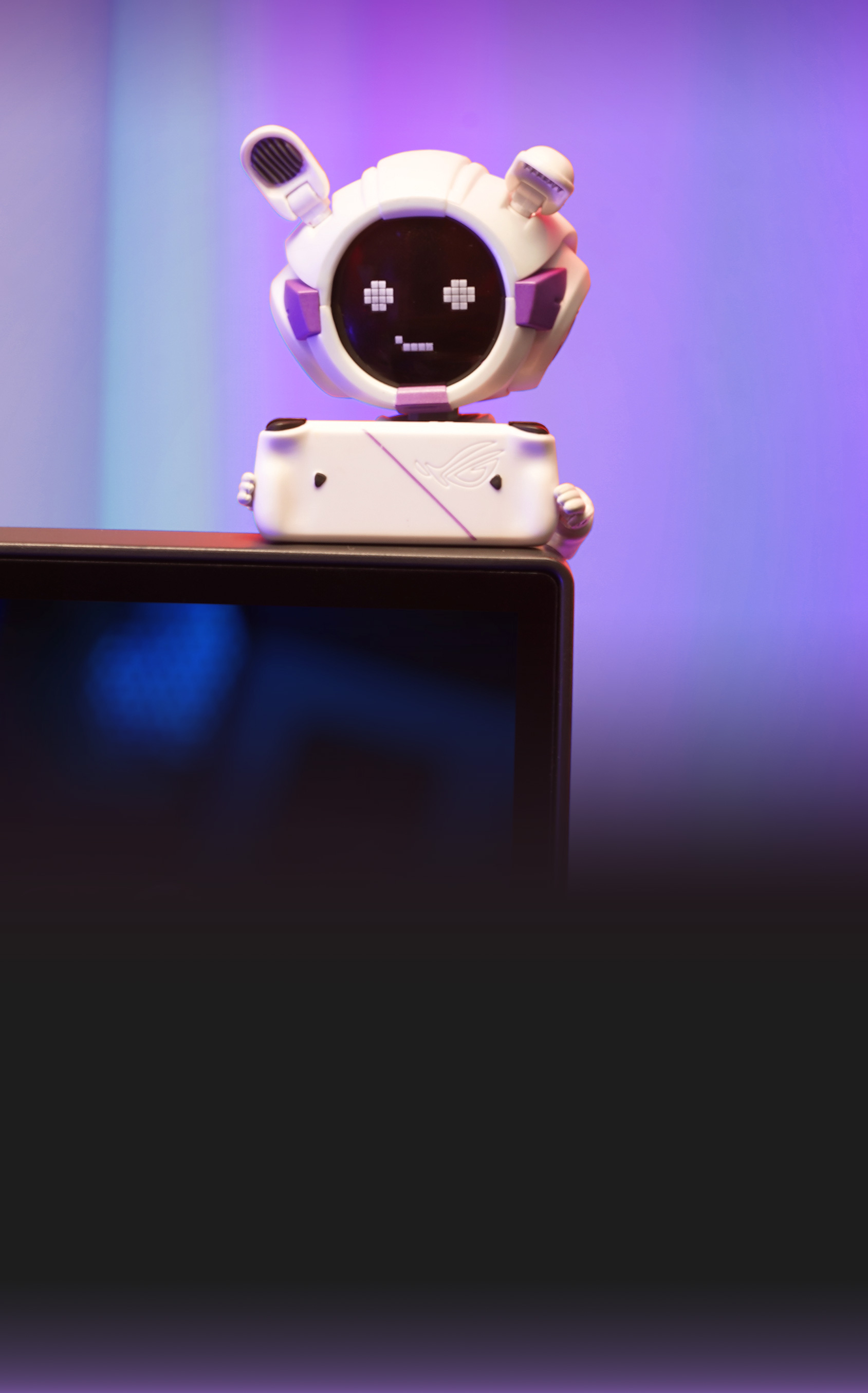 The figure is perched on top of a gaming monitor, displaying a playful pixel smile on its face. The scene highlights OMNI Model White’s fun and tech-savvy personality, making it an ideal gaming desk companion and premium collectible for ROG fans and gamers.