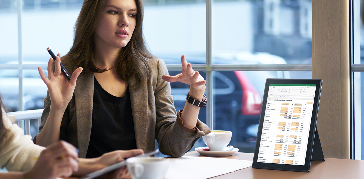 Une femme d’affaires montre à son client un ordinateur portable ExpertBook B3 Detachable.