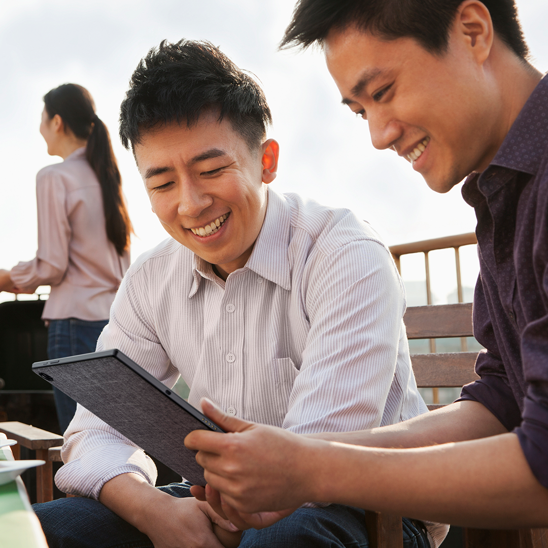 Zwei Geschäftsleute betrachten das ASUS Chromebook Detachable mit einem Lächeln.