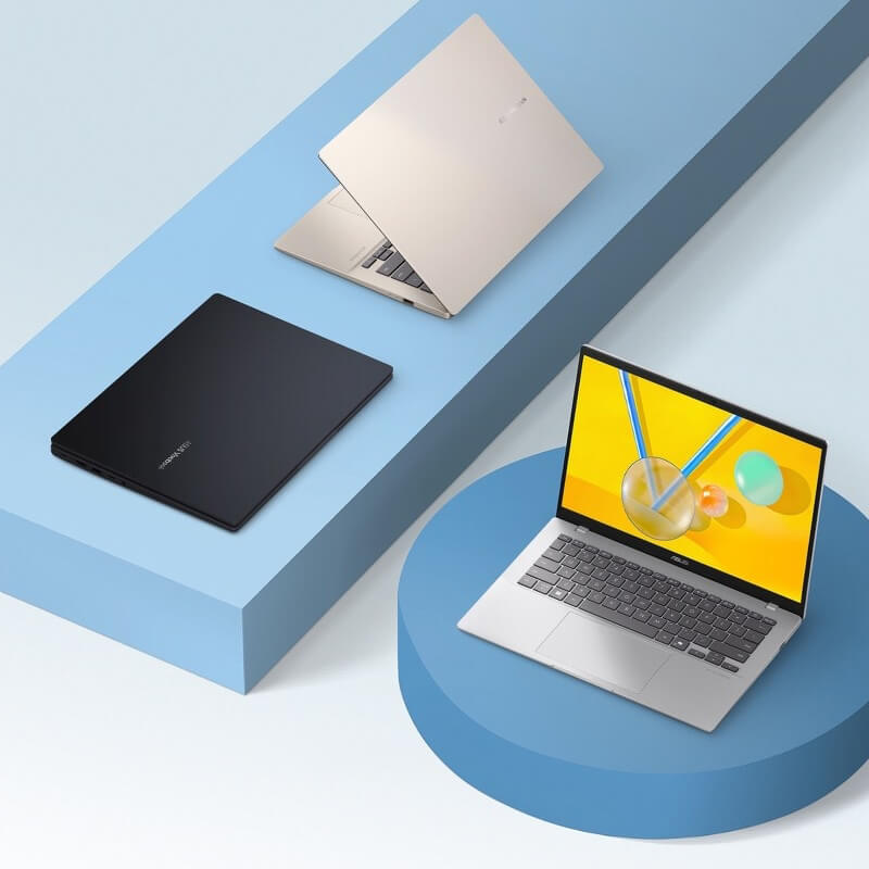 Three ASUS Vivobooks sit on purple geometric shapes.