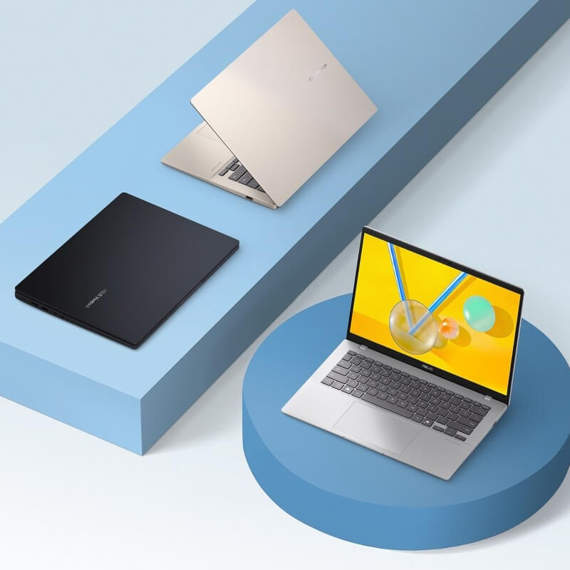 Two ASUS Vivobooks sit on purple geometric shapes.