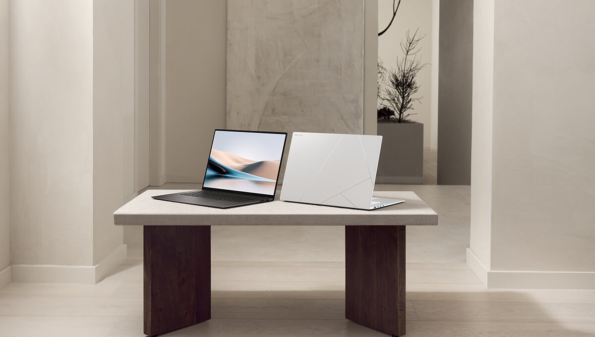 A black Zenbook and a silver Zenbook are placed back-to-back on a marble table in a zen-style setting.