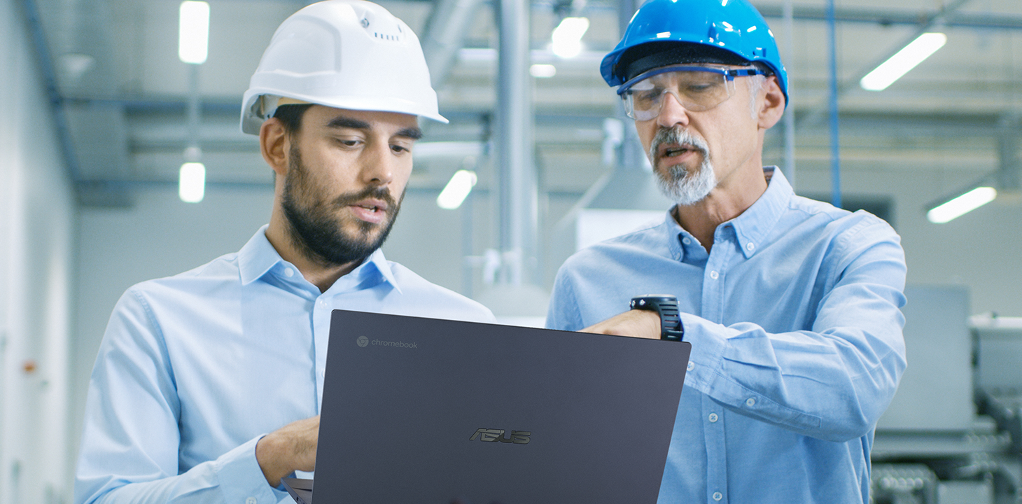 Dos jefes de producción en una fábrica conversan mirando un ASUS Expertbook.