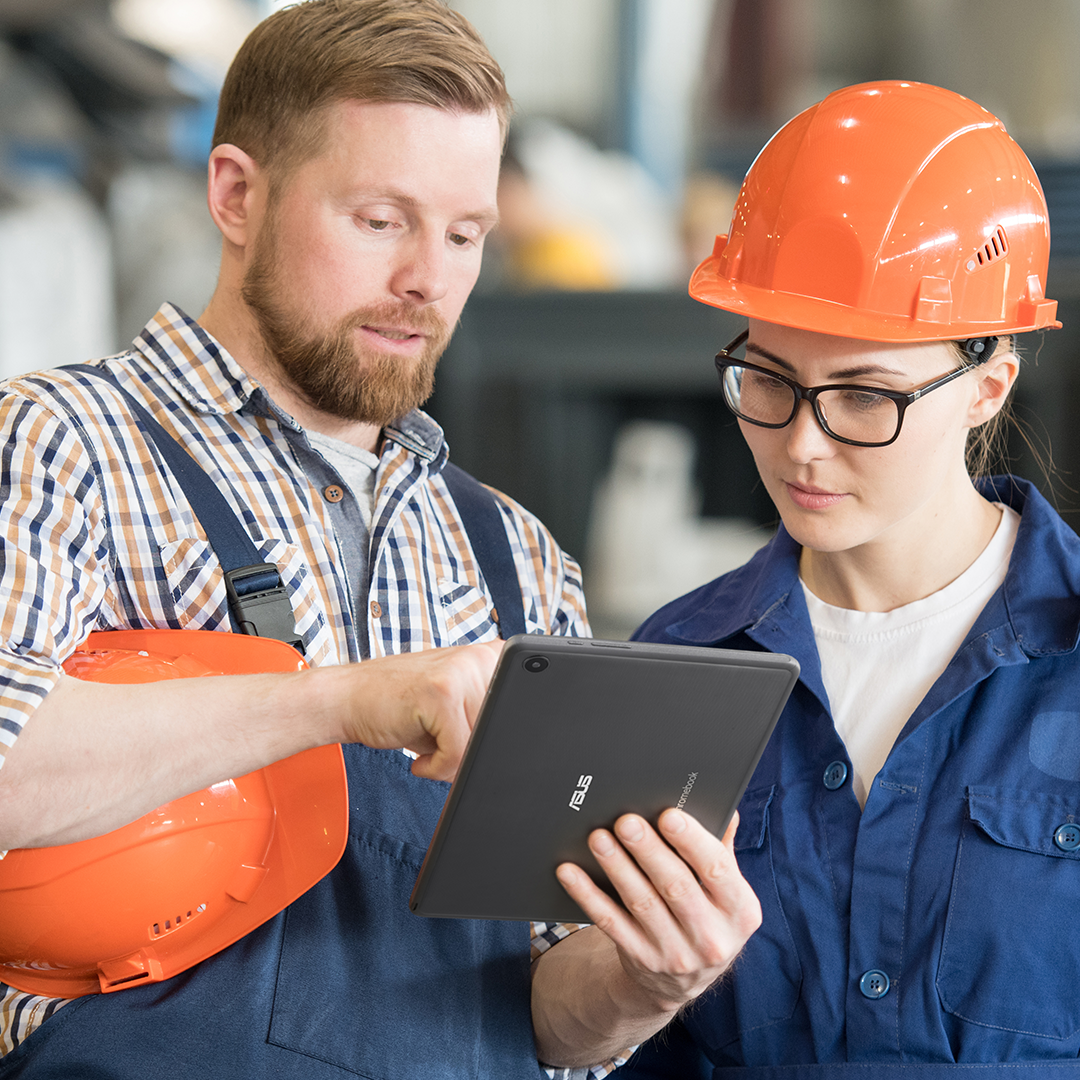 Två produktionschefer tittar på en ASUS Chromebook Detachable och diskuterar något tillsammans i en fabrik.