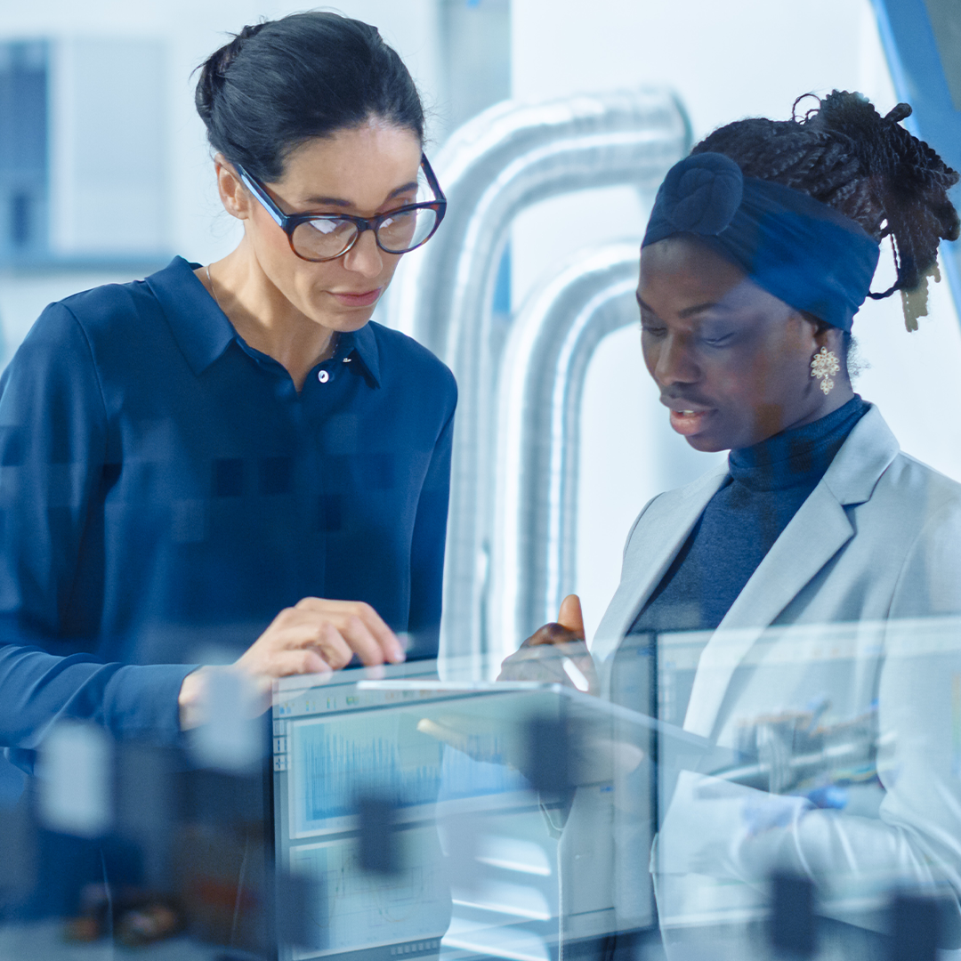 Two employees are checking some information by a tablet in a factory.