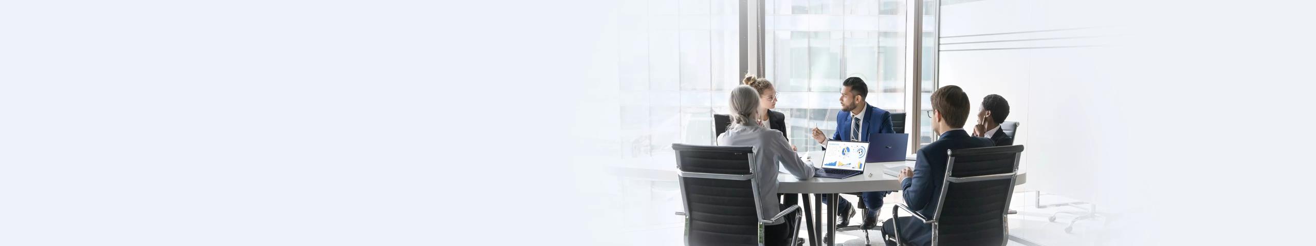 A group of employees are in a meeting room with ASUS ExpertBook laptops on the desk.