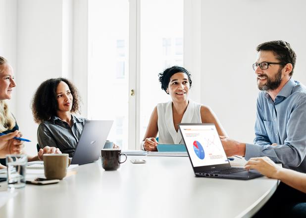 Employees are in a meeting room with ASUS ExpertBook laptops on the desk.