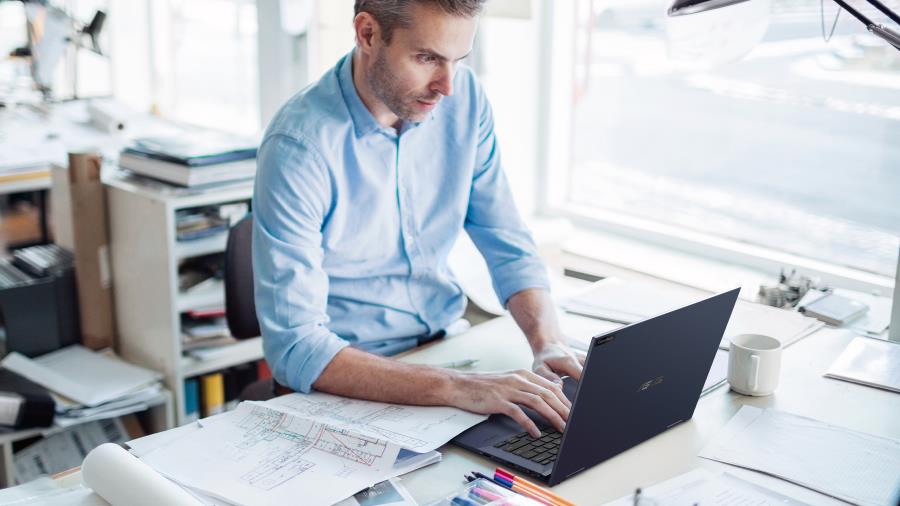 Un uomo d'affari guarda con attenzione il suo ASUS ExpertBook alla scrivania.