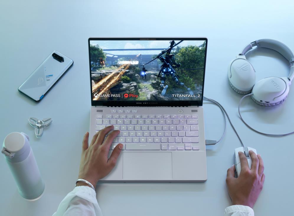 Top down view of a person gaming, with all white accessories next to a white Zephyrus G14.