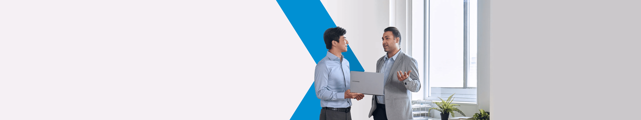 Deux hommes d'affaires discutent ensemble avec un ordinateur portable ASUS ExpertBook à la main.
