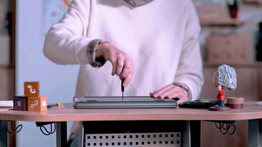 En lärare använder en skruvmejsel för att öppna undersidan av ASUS BR1100 laptop.