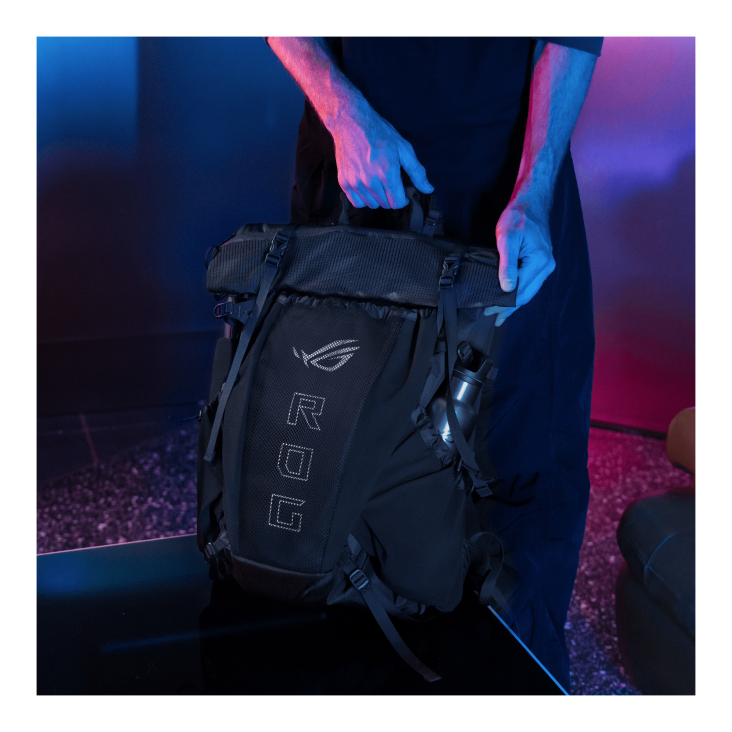 Person holding the top handle of the ROG Archer ErgoAir Gaming Backpack on a table