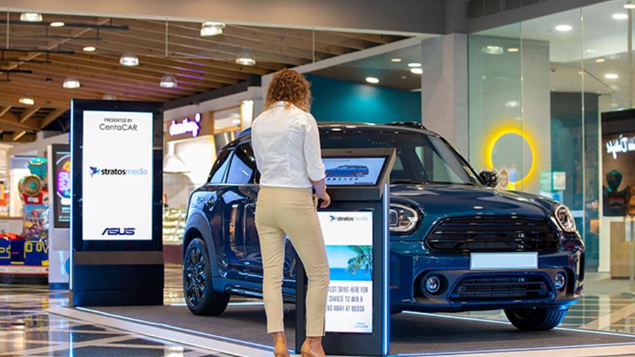 In the car showroom, a digital signage displays product introduction to customer