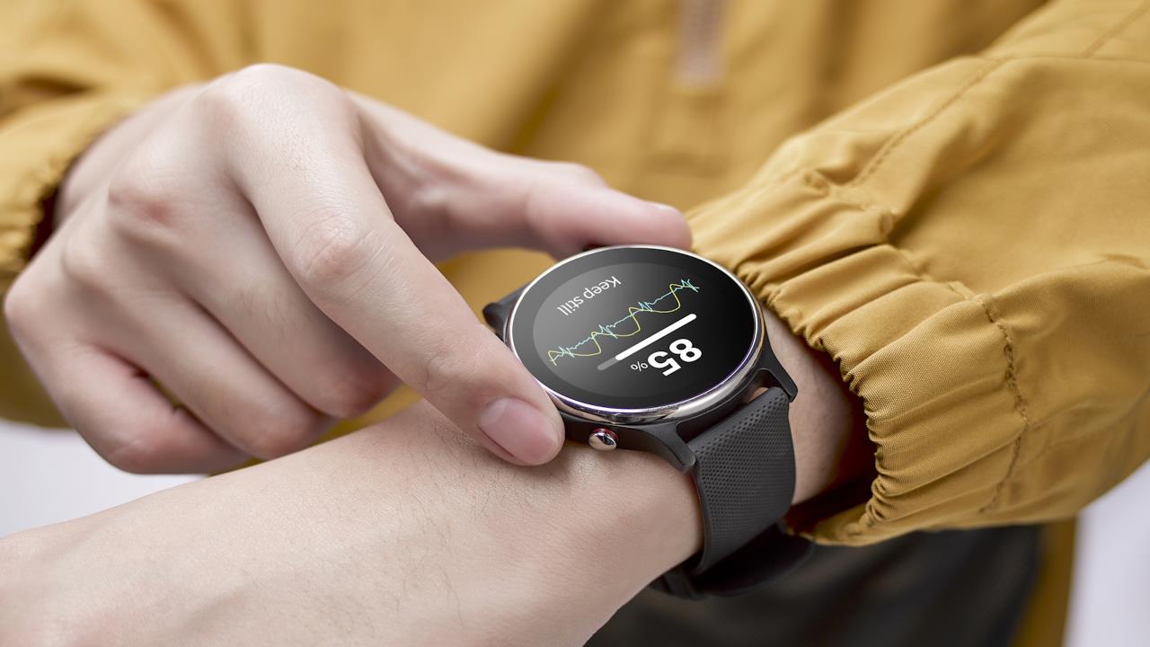 A person in a yellow jacket checks a ASUS VivoWatch 6 smartwatch displaying health data, including an 85% reading and graph. The mood is focused and tech-driven.