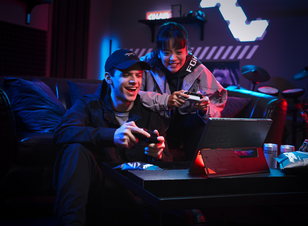 Man and woman seated at a couch, holding controllers, using the Flow Z13 as a gaming system.