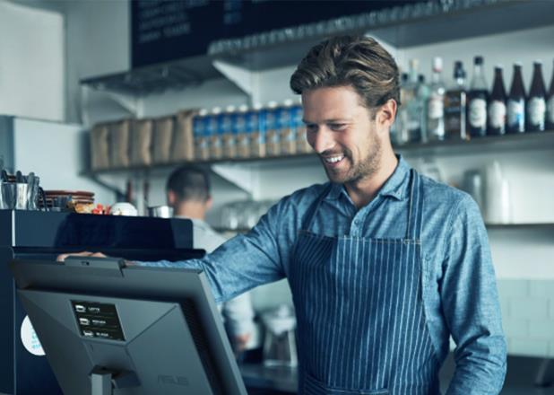 A smiling man standing at the counter in a cafe using POS to check out