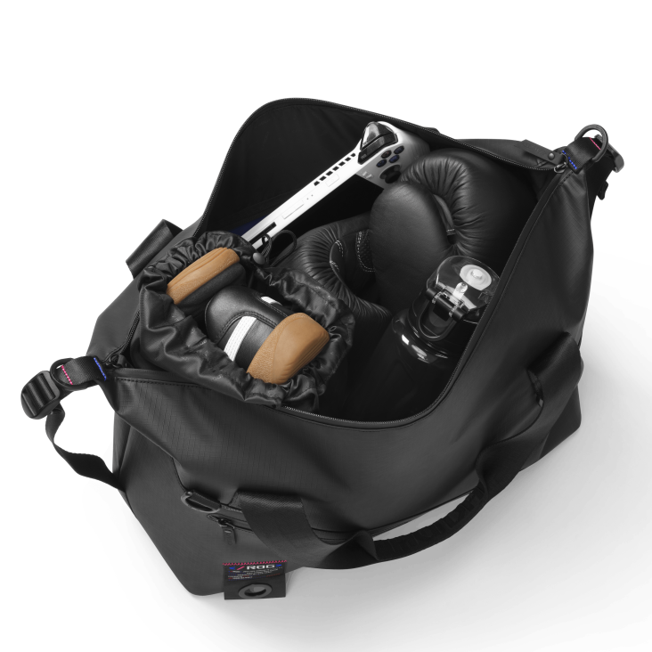 SLASH Duffle Bag on a white background, with a top down view of the bag opened and multiple items inside