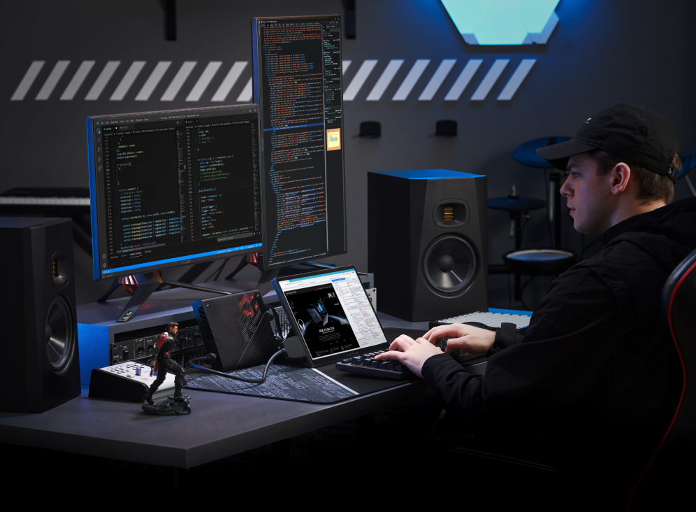 Man at a workstation with external keyboard, Flow Z13, XG Mobile, and dual monitors, working on a coding project.